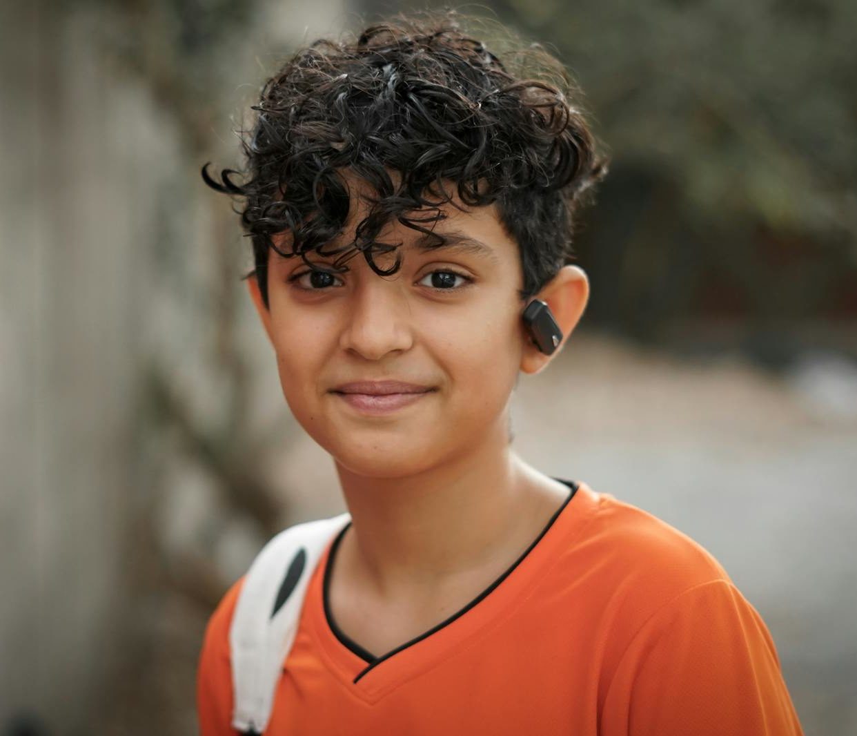 Boy in Orange Shirt Smiling at the Camera