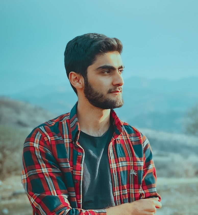 man in red and black plaid dress shirt standing on brown field during daytime